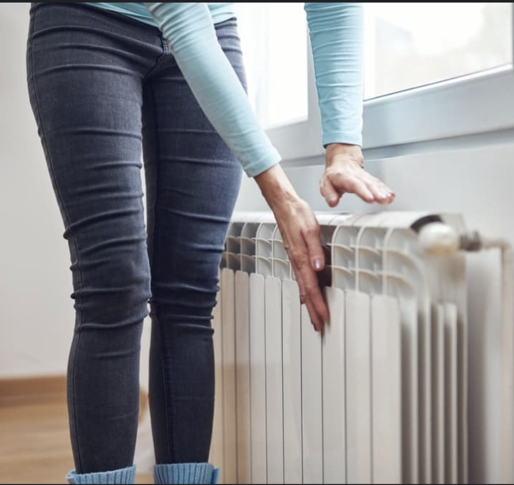 Woman checking radiator for warm air