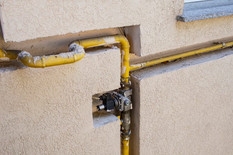Styrofoam insulation around gas pipes in a wall.