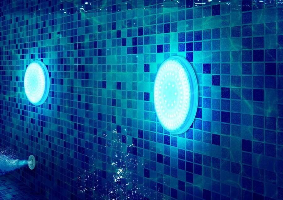Pool lights underwater against a tiled wall