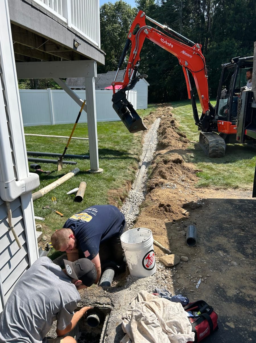 Plumbers digging into ground for water line repair.
