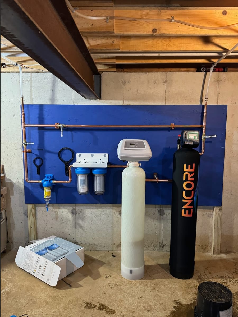 Water softener system set up next to a water heating unit in the basement.