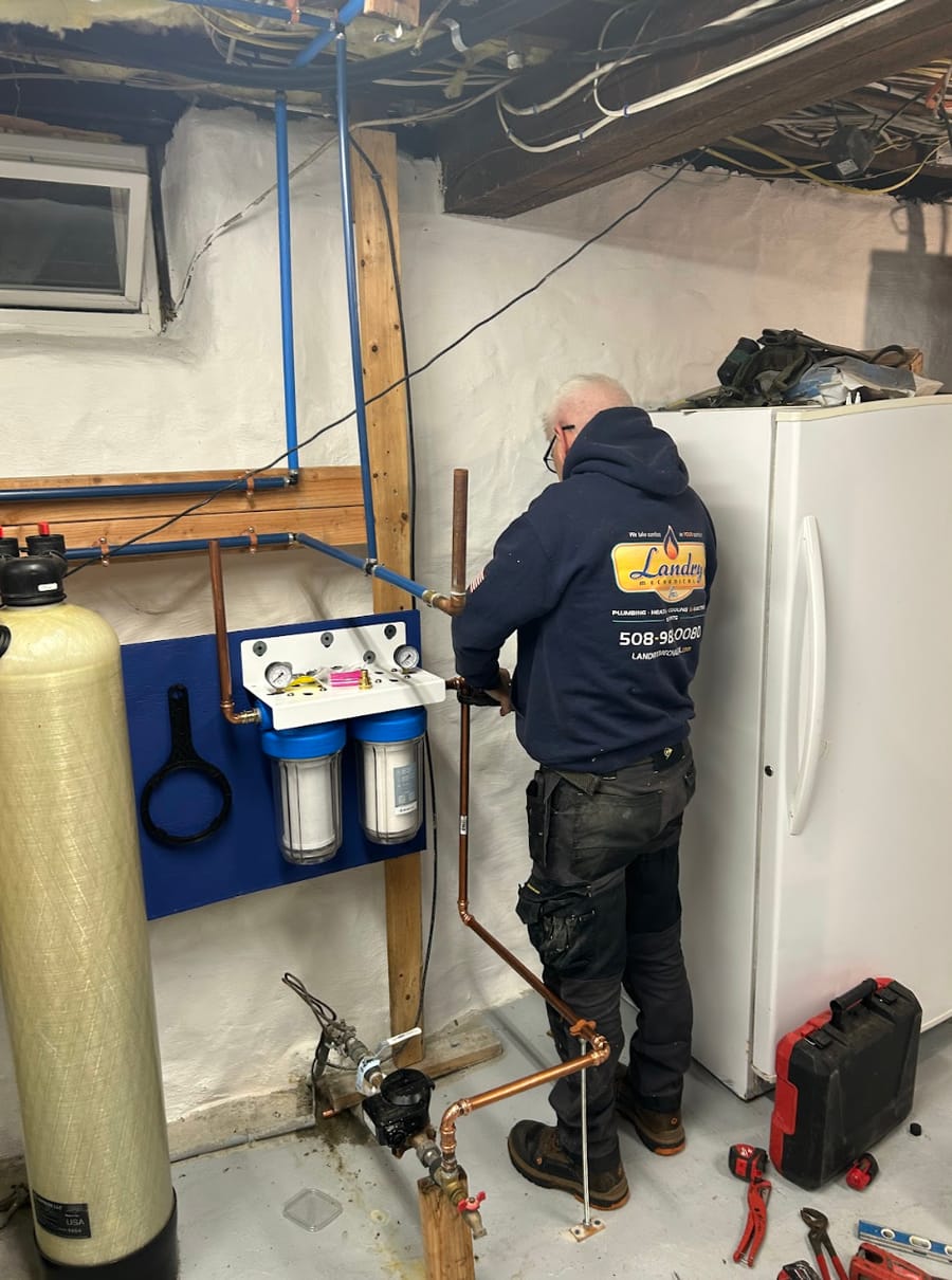 A Landry plumber setting up a water treatment unit in a home's basement.