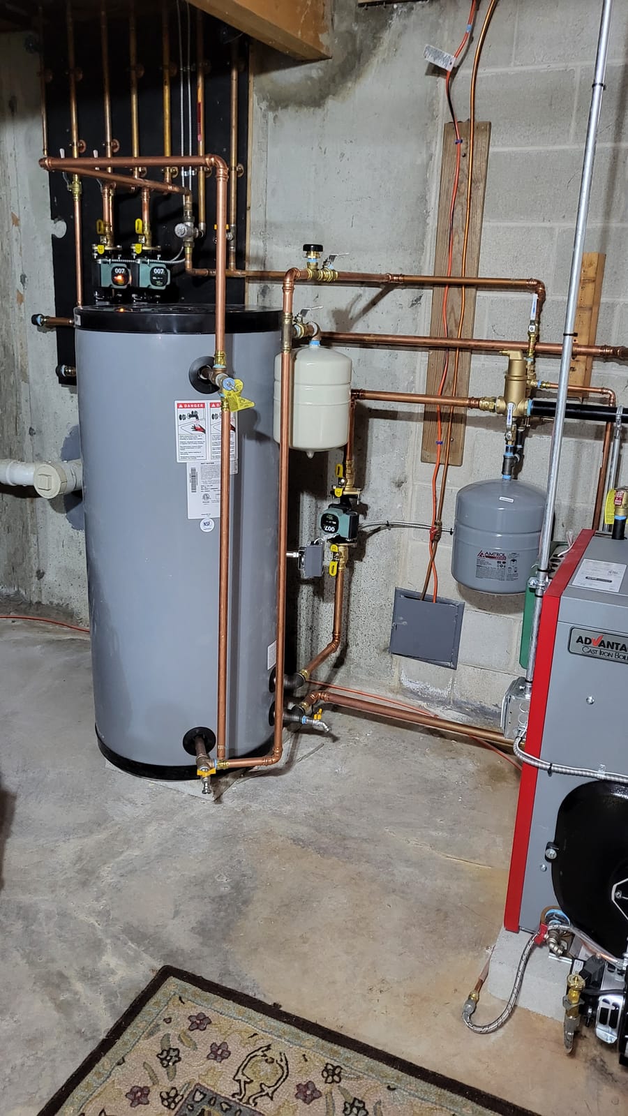 residential water heating system with copper piping, pressure tanks, and a modern boiler