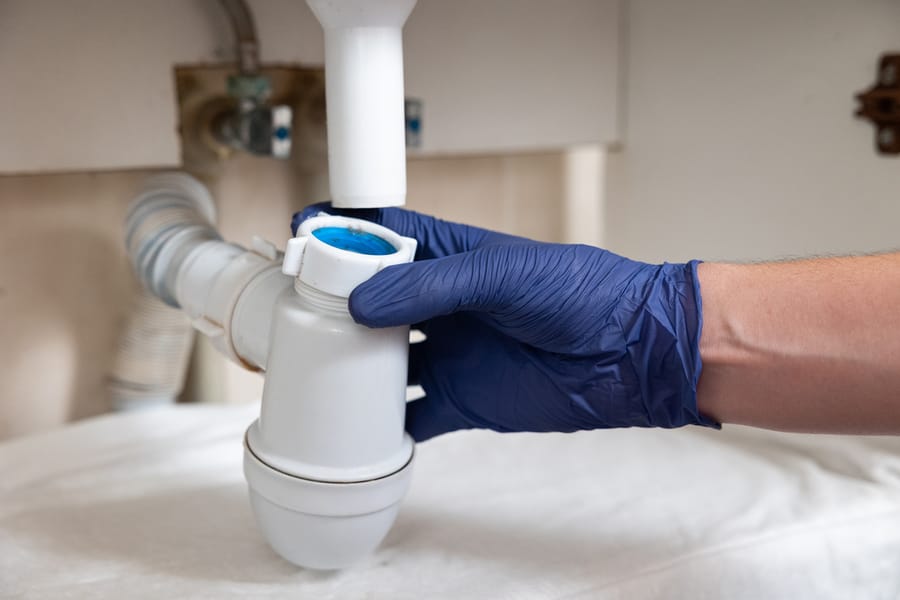 Gloved hand leaning a drain.