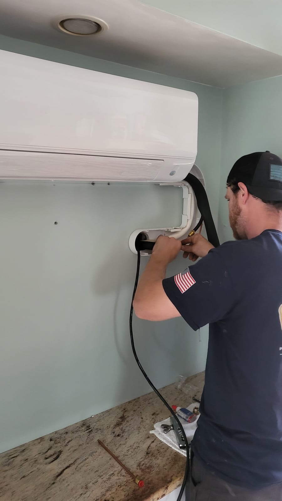 HVAC tech working on mini-split on wall.