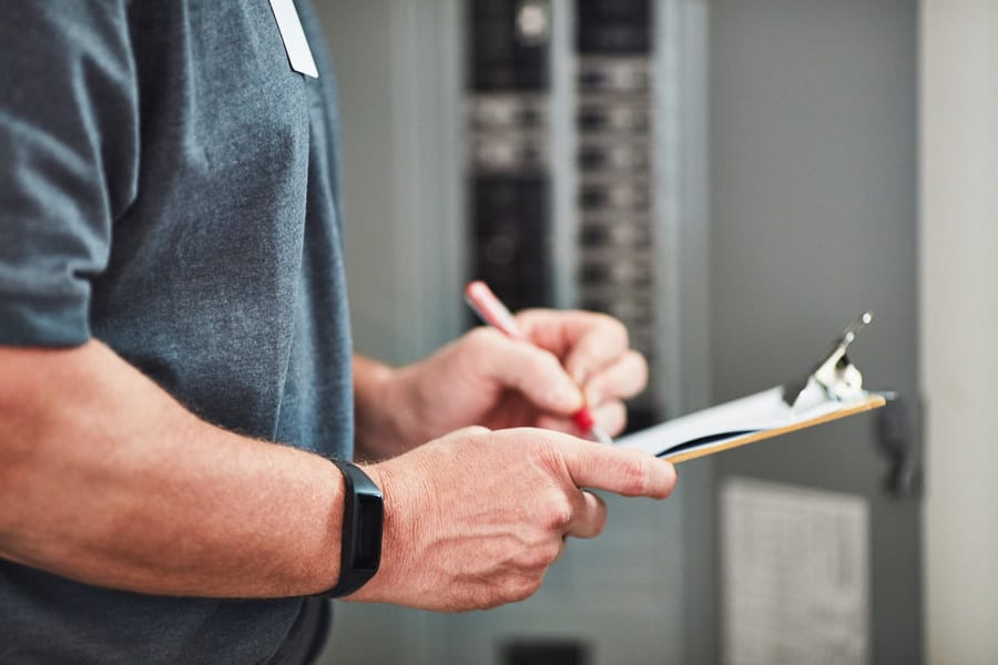 Man writing on a clipboard during an electrical safety inspection