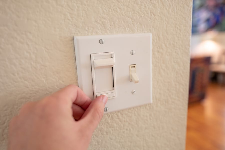 hand turning a light switch dimmer on