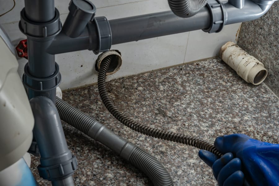 Plumber using equipment to remove grease from commercial drain pipe.